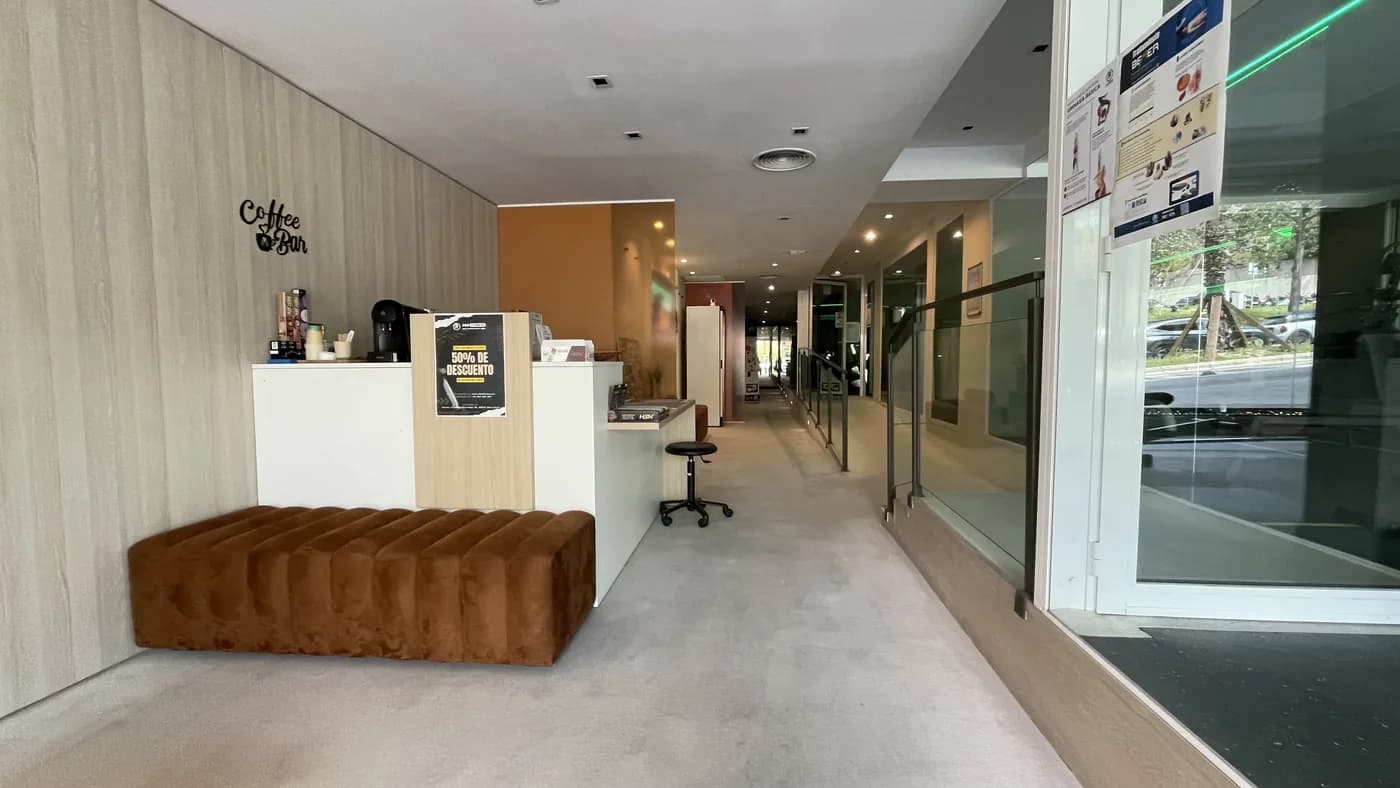 Recepción de 360Fitness Barcelona: el mostrador, el banco tapizado y la barra de café junto a la entrada.